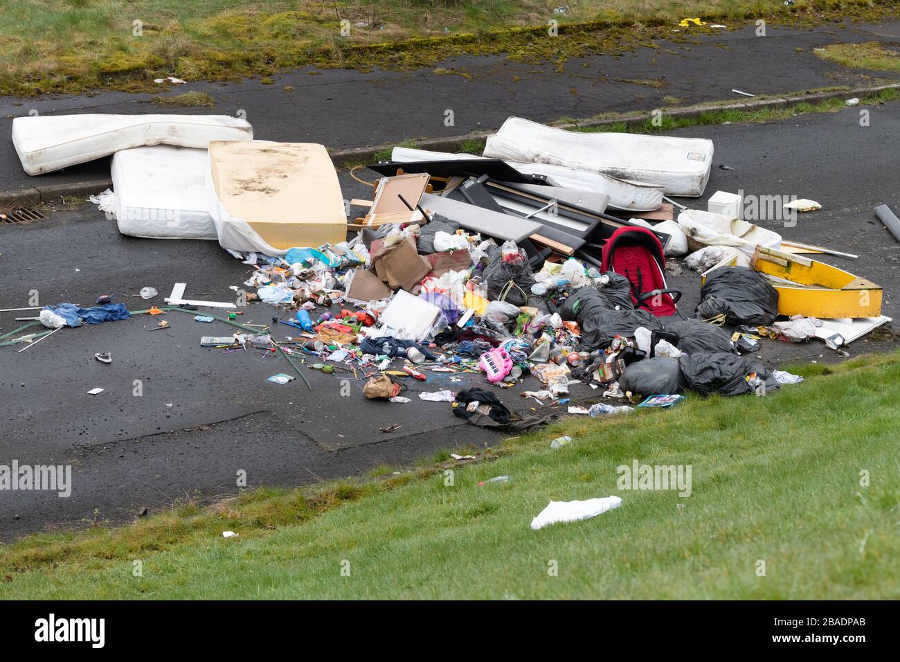 fly tipping uk - large pile of household rubbish including childrens toys and mattresses - Easterhouse, Glasgow, Scotland, UK Stock Photo