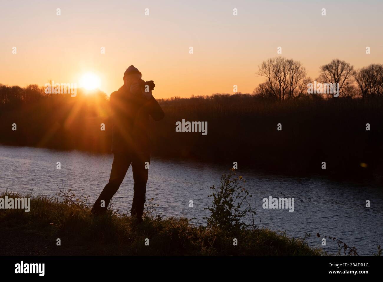 silhouette of man against the sun with camera at sunset in nature ...