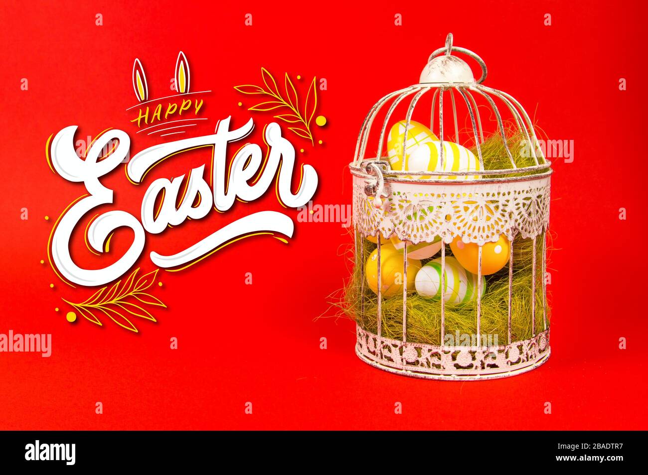 White bird cage with Easter eggs in it on a red background Stock Photo