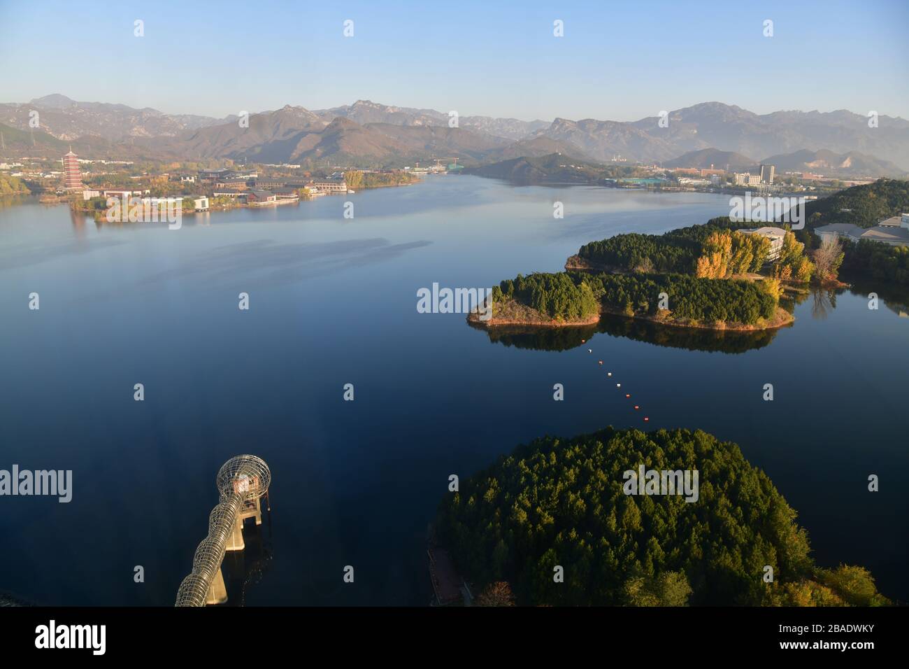 Bird’s eye view of Yanqi Lake with its tranquil waters, the large pagoda on the other side of the lake and portions of the great wall of China barely Stock Photo