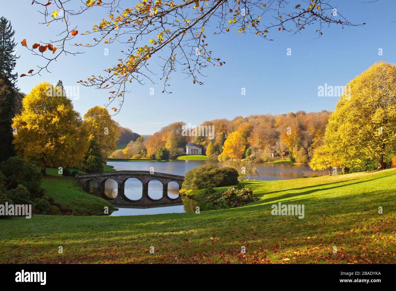 Brilliant autumn colour surrounds the lake and Palladian Bridge in Stourhead Gardens; Wiltshire; England; UK Stock Photo