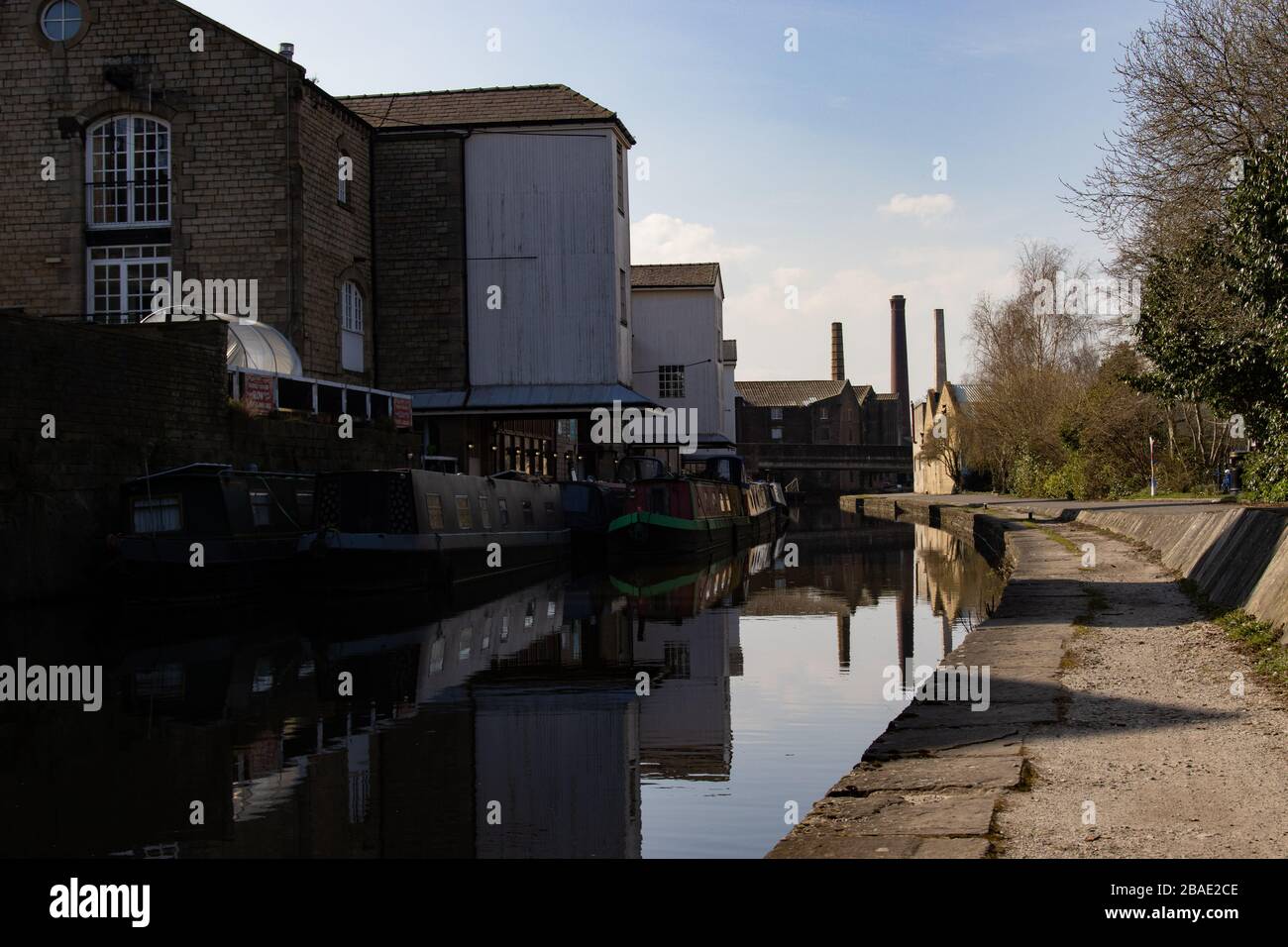 SALTAIRE, ENGLAND - 25/3/2020 - A view of mill chimneys seen in the distance at Saltaire from Shipley in a traditional canal scene during COVID-19 Stock Photo