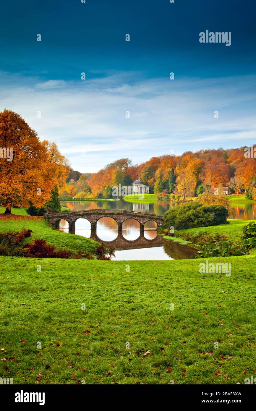 Brilliant autumn colour surrounds the lake and Palladian Bridge in Stourhead Gardens, Wiltshire, England, UK Stock Photo