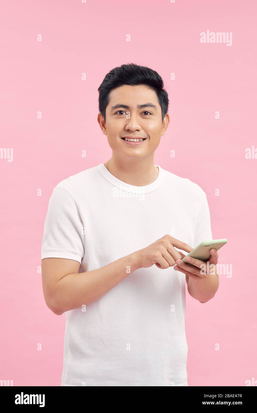 Smiling young good looking Asian man using smartphone to get in touch ...