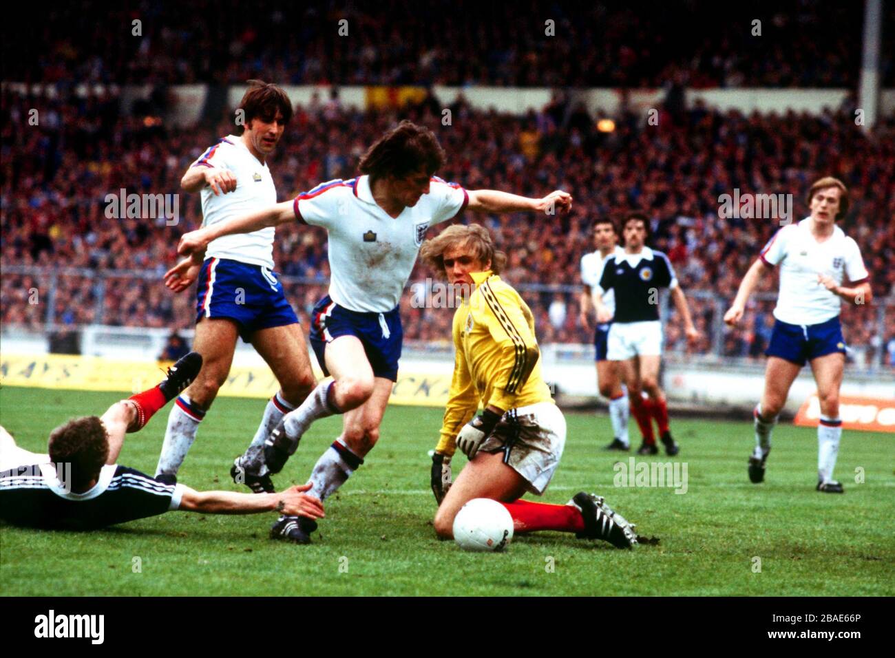 England's Steve Coppell (third left) rounds Scotland goalkeeper George Wood (centre) to score, as teammates Peter Barnes (right) and Bob Latchford (second left) look on Stock Photo