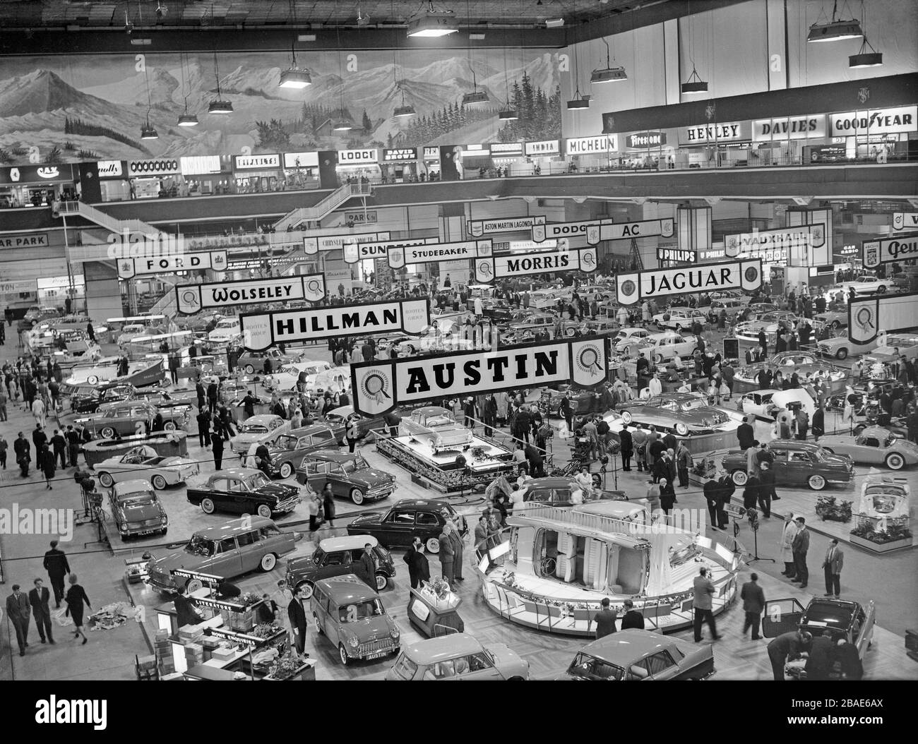 Vintage black and white photograph showing a view of the London Motor Show at Earls Court in 1961. Manufacturers visible include Jaguar, Austin, Hillman, Wolseley, Ford, Morris, Studebaker, Sunbeam, Vauxhall, AC, Dodge. Stock Photo