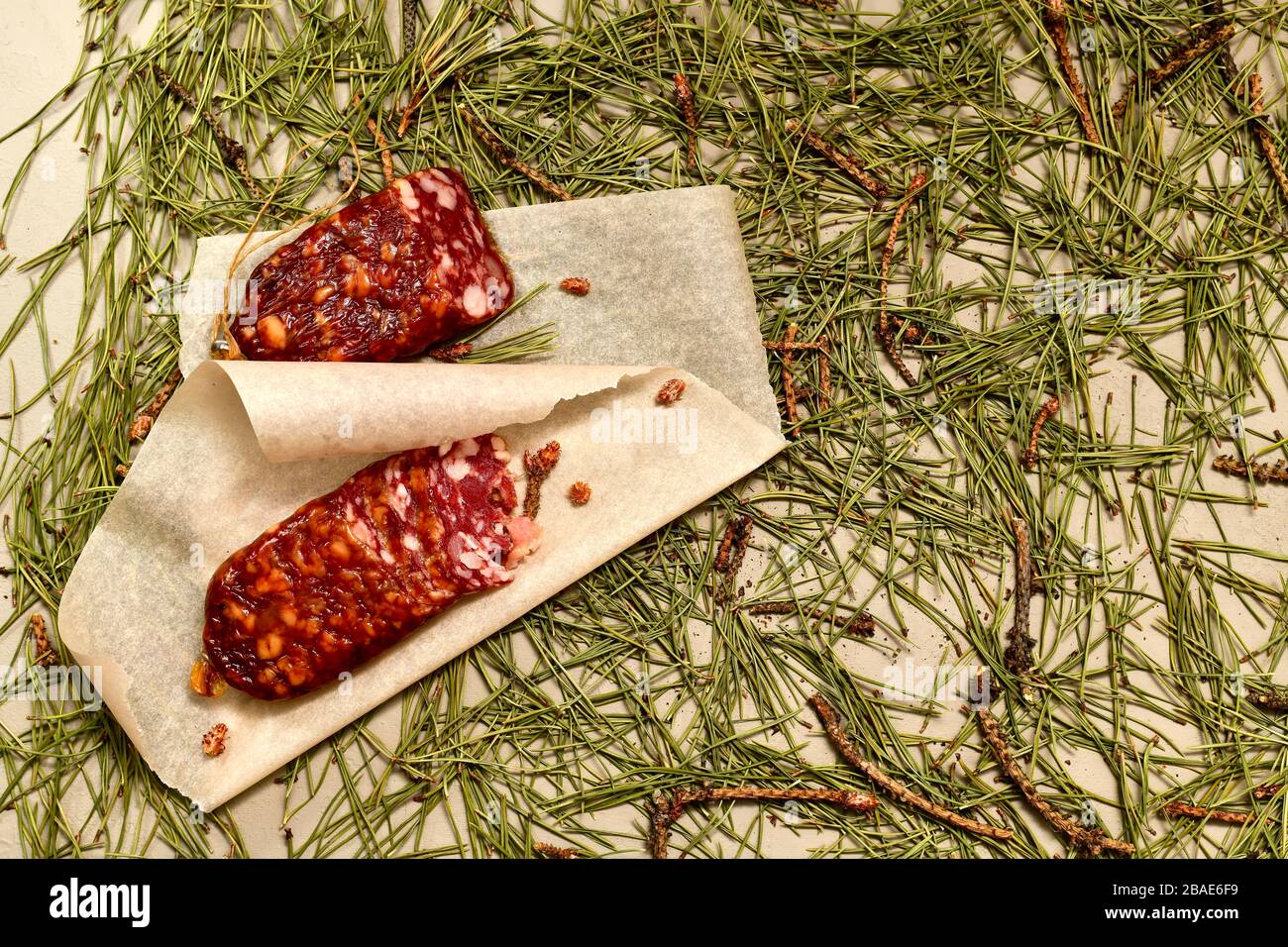 Dried sausage made of beaver meat cut with slices on parchment with ...