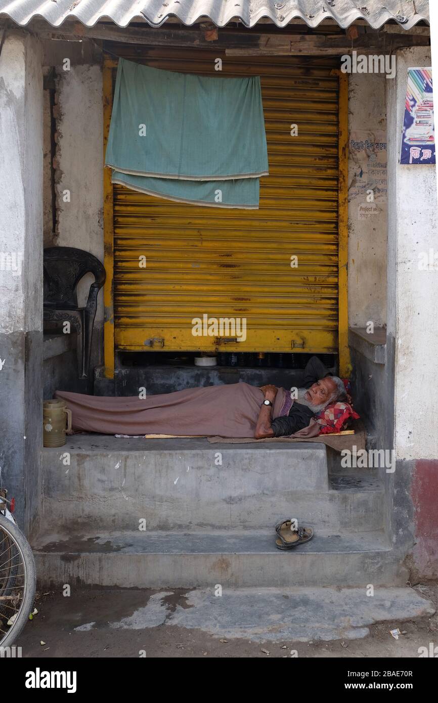 A man sleeps in front of his shop in Chunakhali village, West Bengal, India Stock Photo