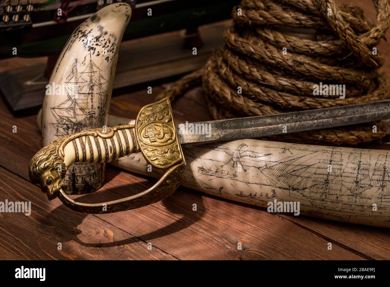 Stlll life of the 19th century sea voyage with an etching on a walrus tusk, rope and English naval sabre Stock Photo