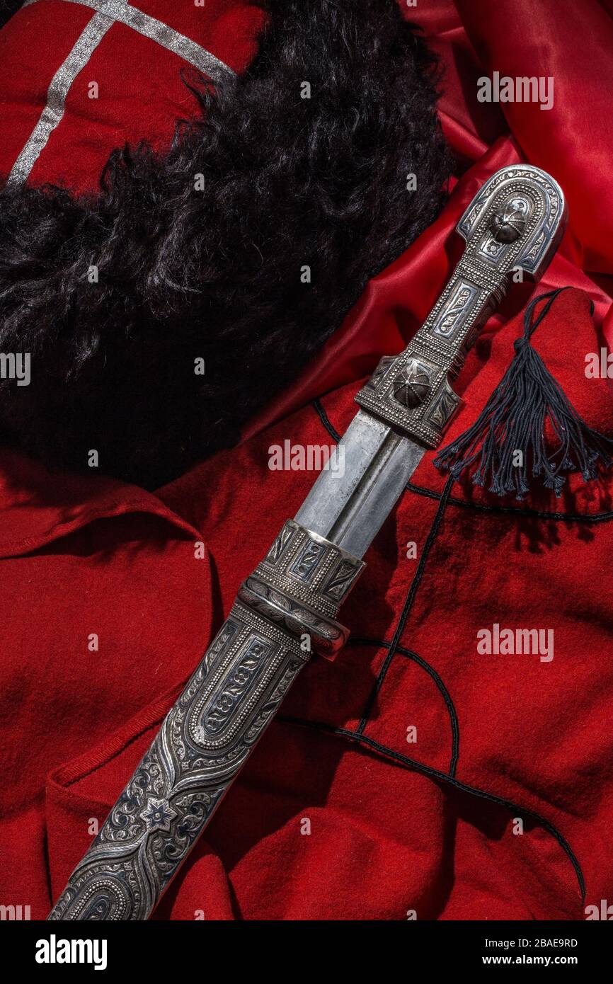 Beautiful example of caucasian dagger on red cossack beshmet background. 19th century (Time of Russian-Caucasian wars (1816-1864)). Russia Stock Photo