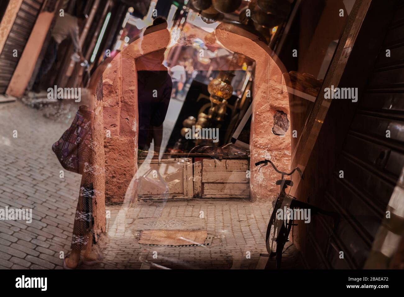 Busy scene inside the medina (old town), showing a woman with shopping bags walking, a lamp shop, and a bicycle leaning against a closed shop, Novembe Stock Photo