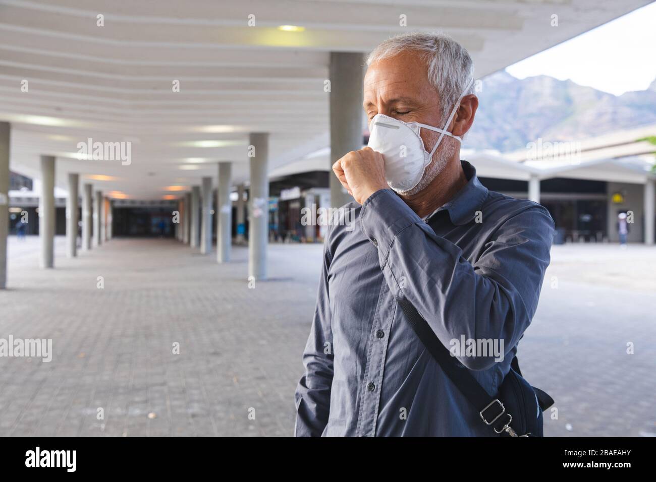 Middle aged man wearing Coronavirus Covid19 mask coughing Stock Photo