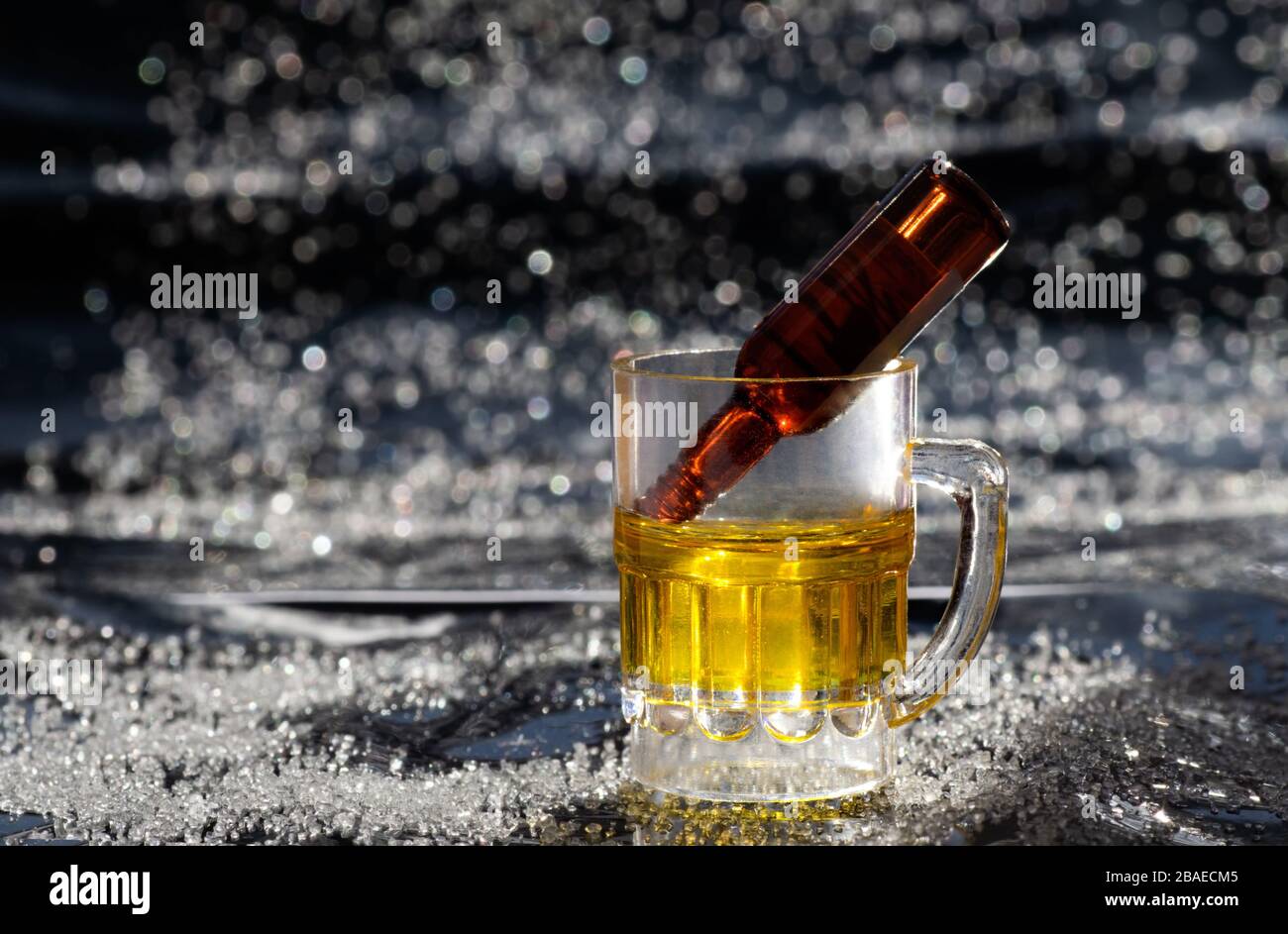A miniature bottle in a small beer mug. Alcoholism and moderate consumption problem Stock Photo