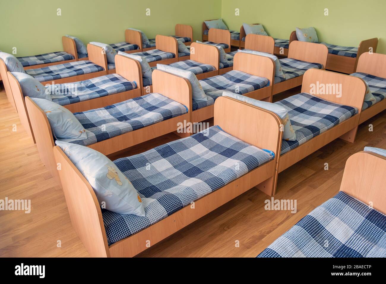 Many small beds with fresh linen in daycare preschool empty