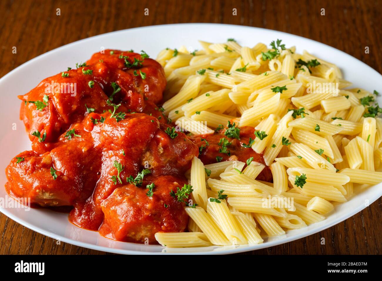 Meatballs in tomato sauce with small penne pasta on plate Stock Photo