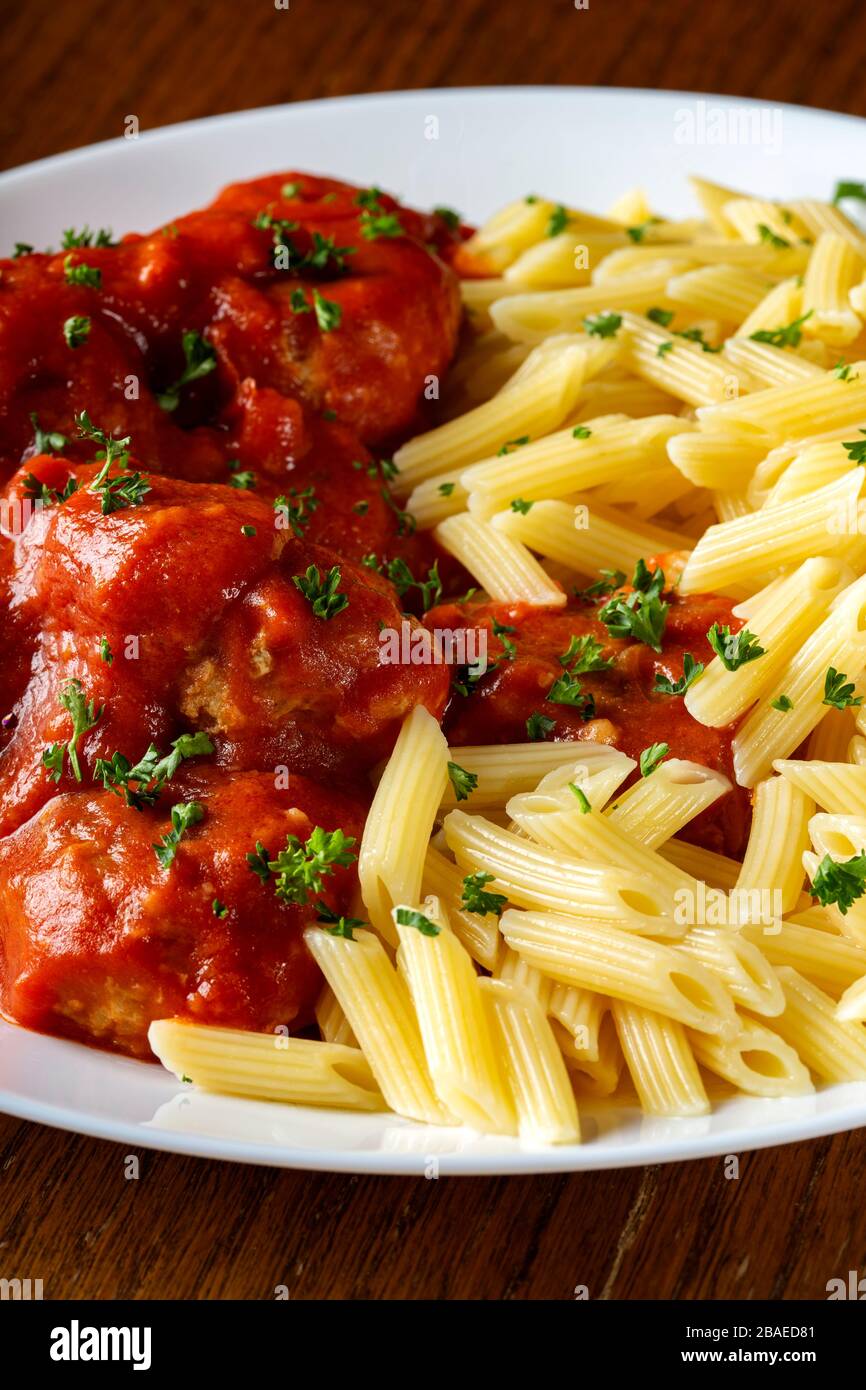 Meatballs in tomato sauce with small penne pasta on plate Stock Photo