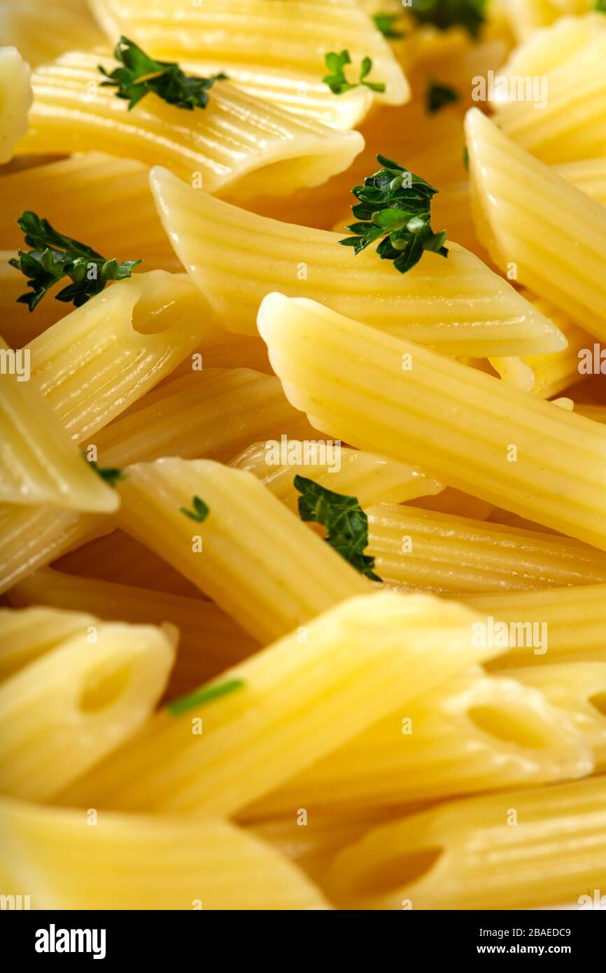 Boiled penne pasta with green chopped parsley - close up view Stock Photo