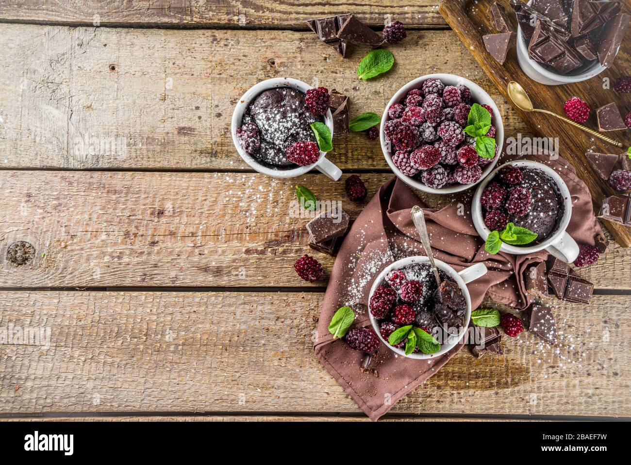 Homemade chocolate mug cake with blackberry. Breakfast easy snack recipe, chocolate non dairy cake in mugs, with blackberry, sugar powder and mint, wo Stock Photo