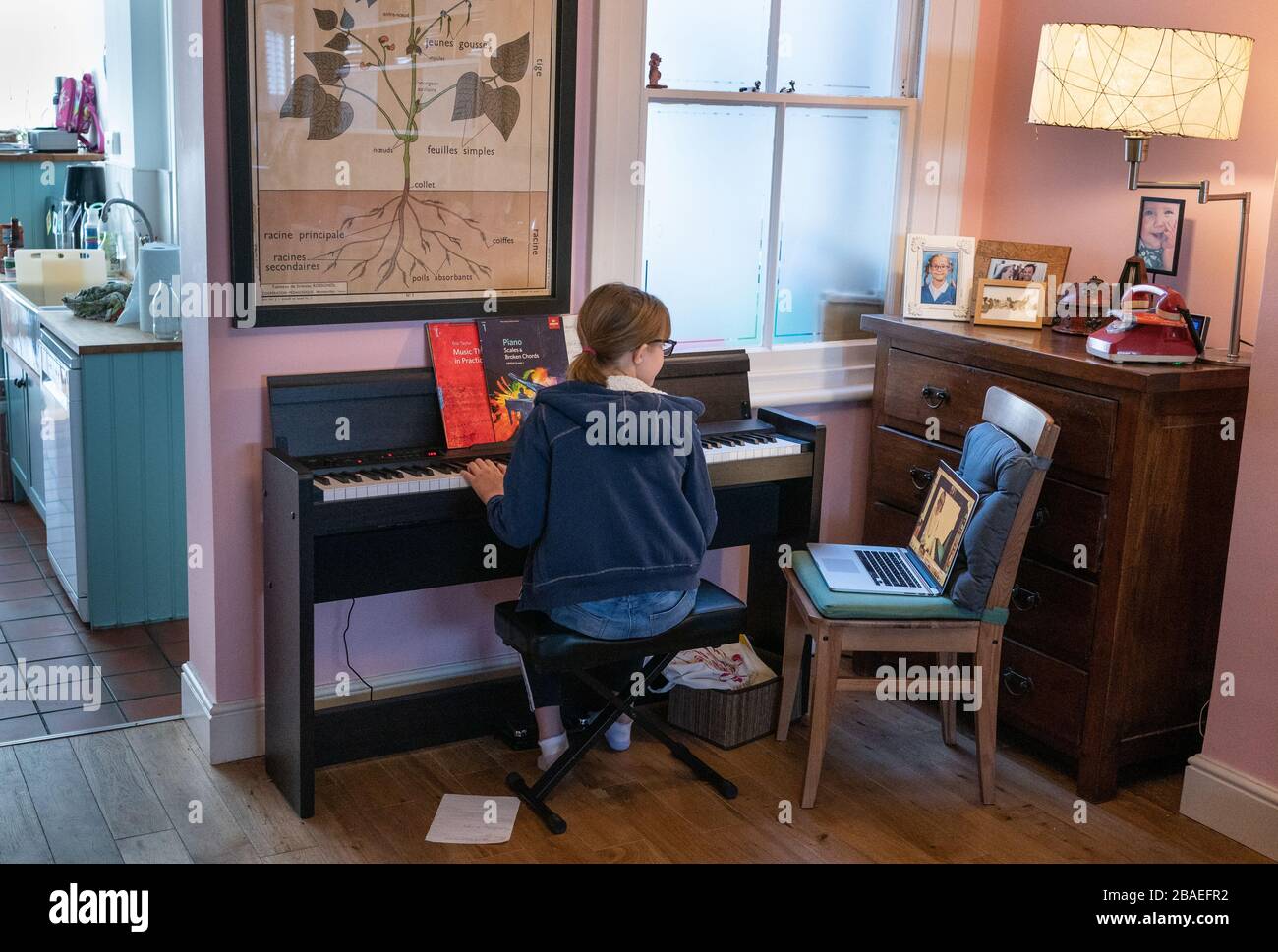 A young girl plays piano for her teacher who was watching via a Zoom call on March 25, 2020 in Rickmansworth, Hertfordshire, UK. © Suzanne Plunk Stock Photo