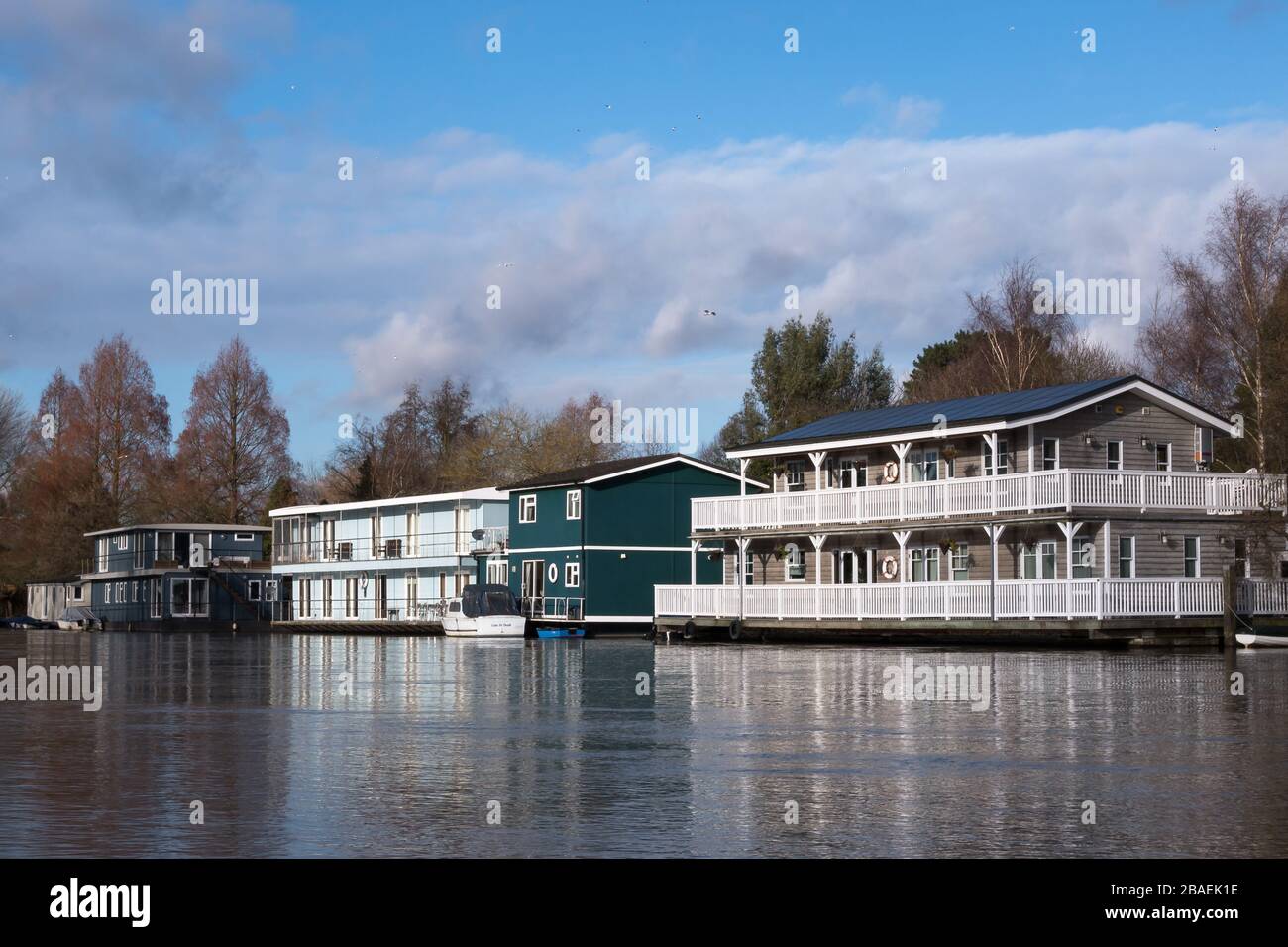 Floating houseboats moored along the shore of the River Thames near