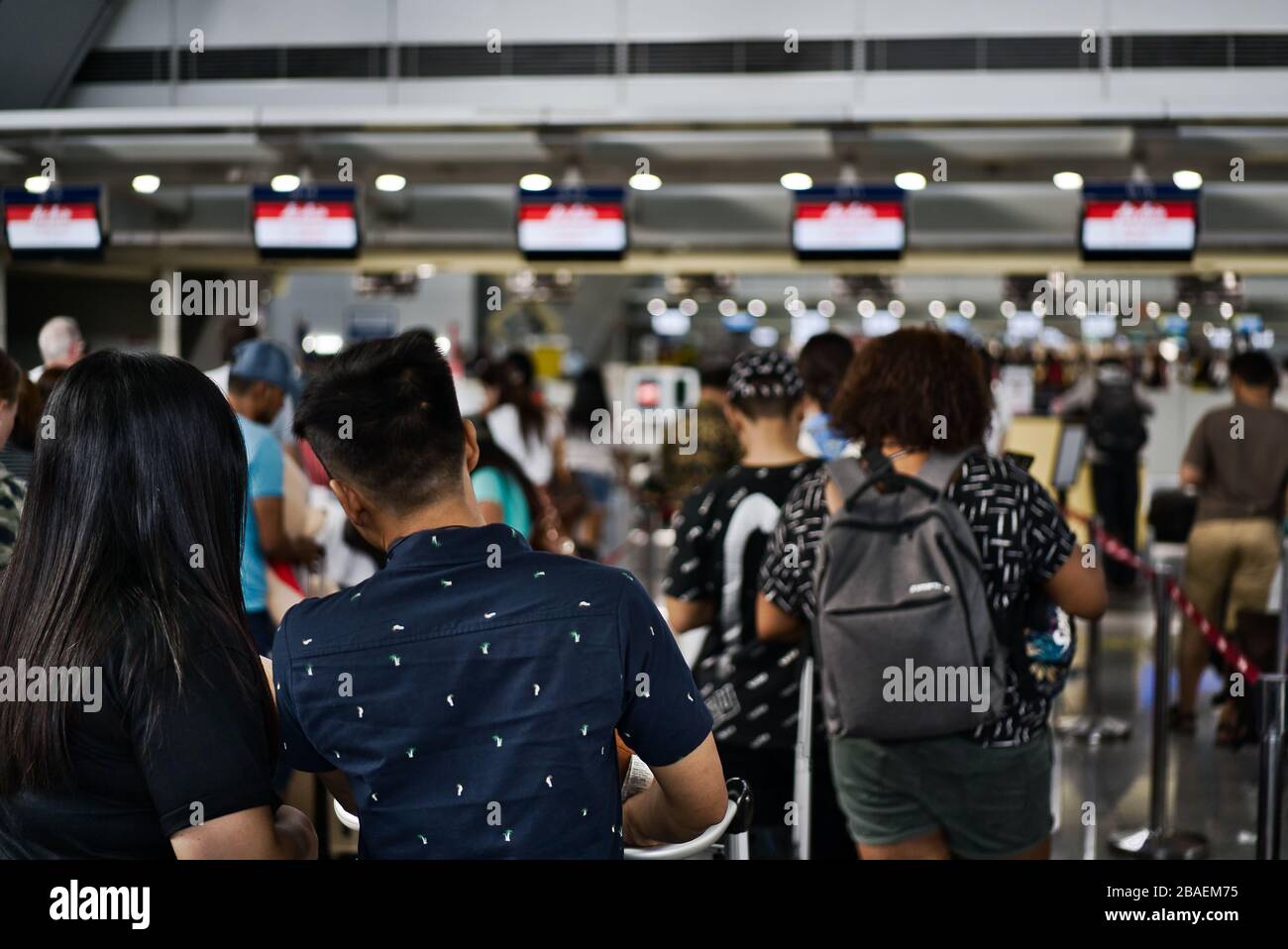 Blurred photo of passengers looking at the flights panel of an airport to confirm the status of their flights. Stock Photo