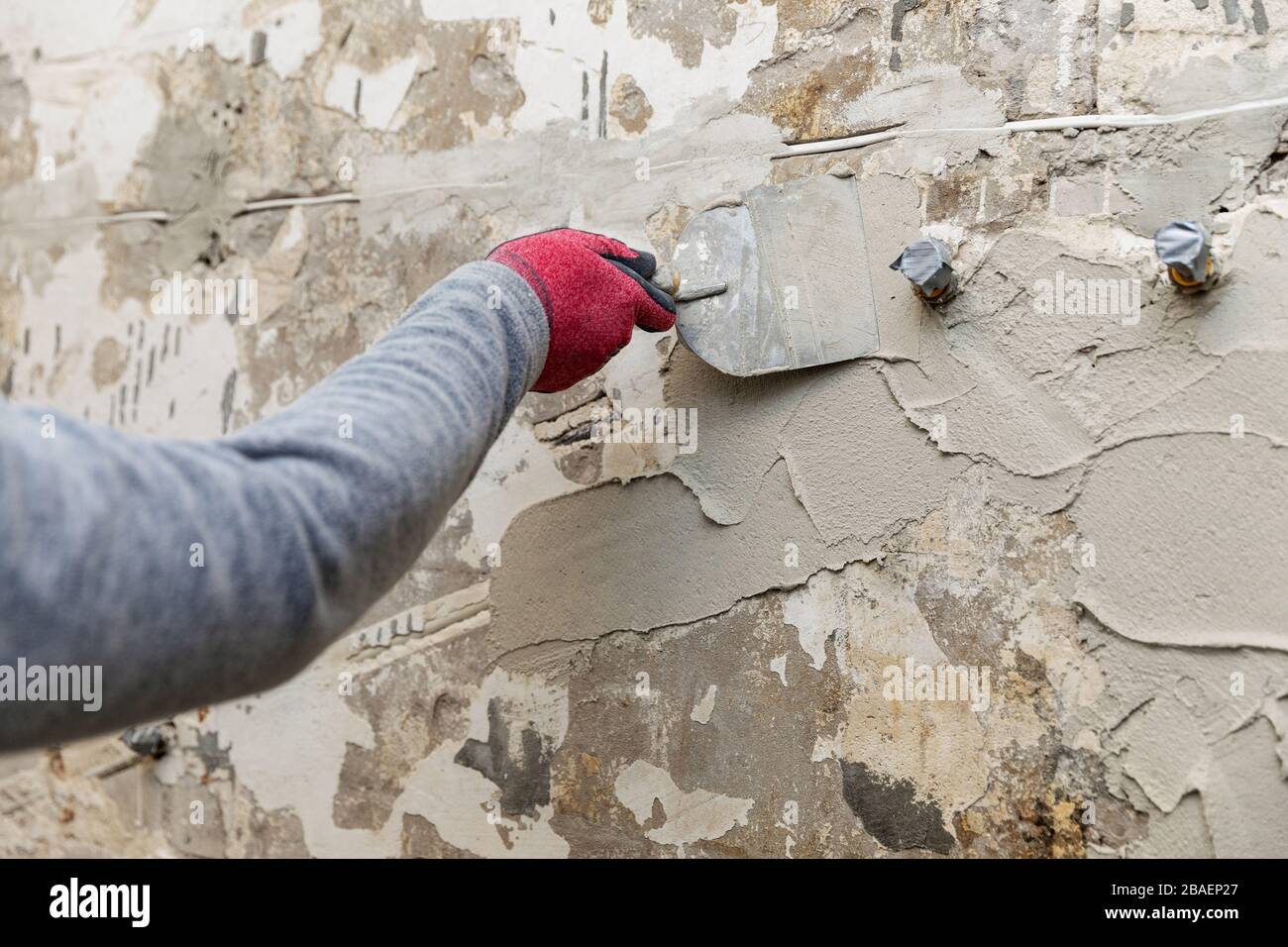 construction worker applying plaster on the old bathroom wall with spatula Stock Photo
