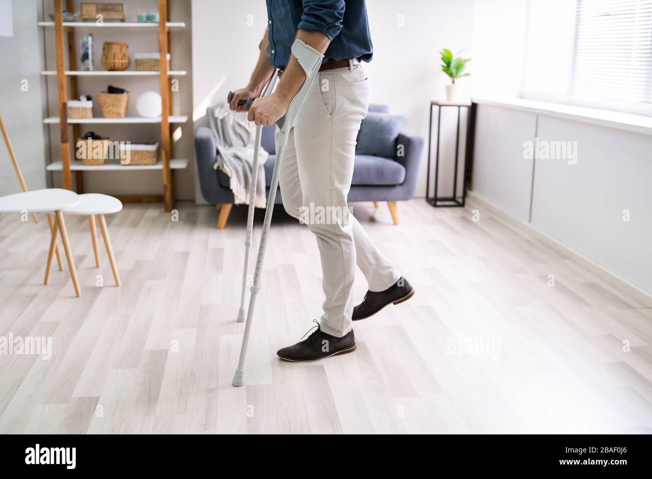 Disabled Man Using Crutches To Walk At Home Stock Photo Alamy