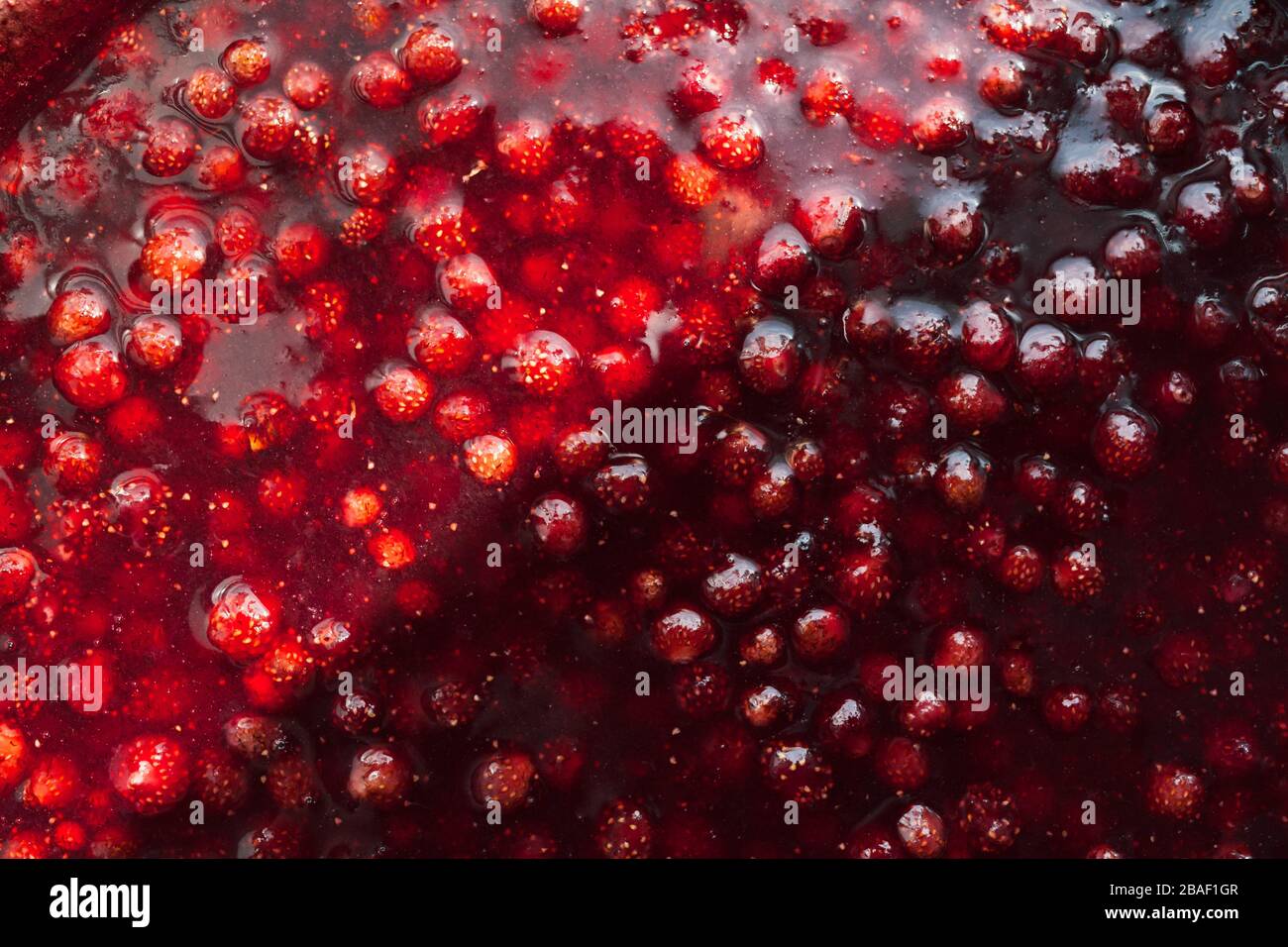strawberry jam texture divided in half by a solar flare, food background gorisontal Stock Photo