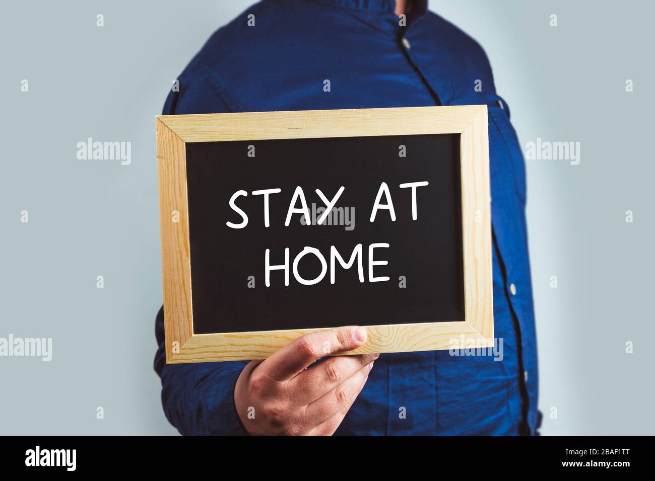 man holding a chalkboard with the words Words Stay At Home Stock Photo