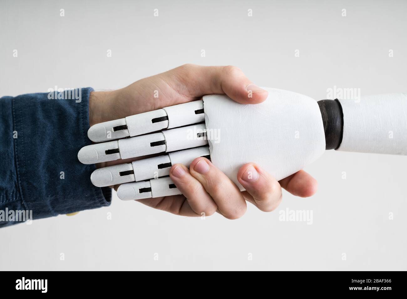 Close-up Of Businessperson Shaking Hands With Robot Stock Photo