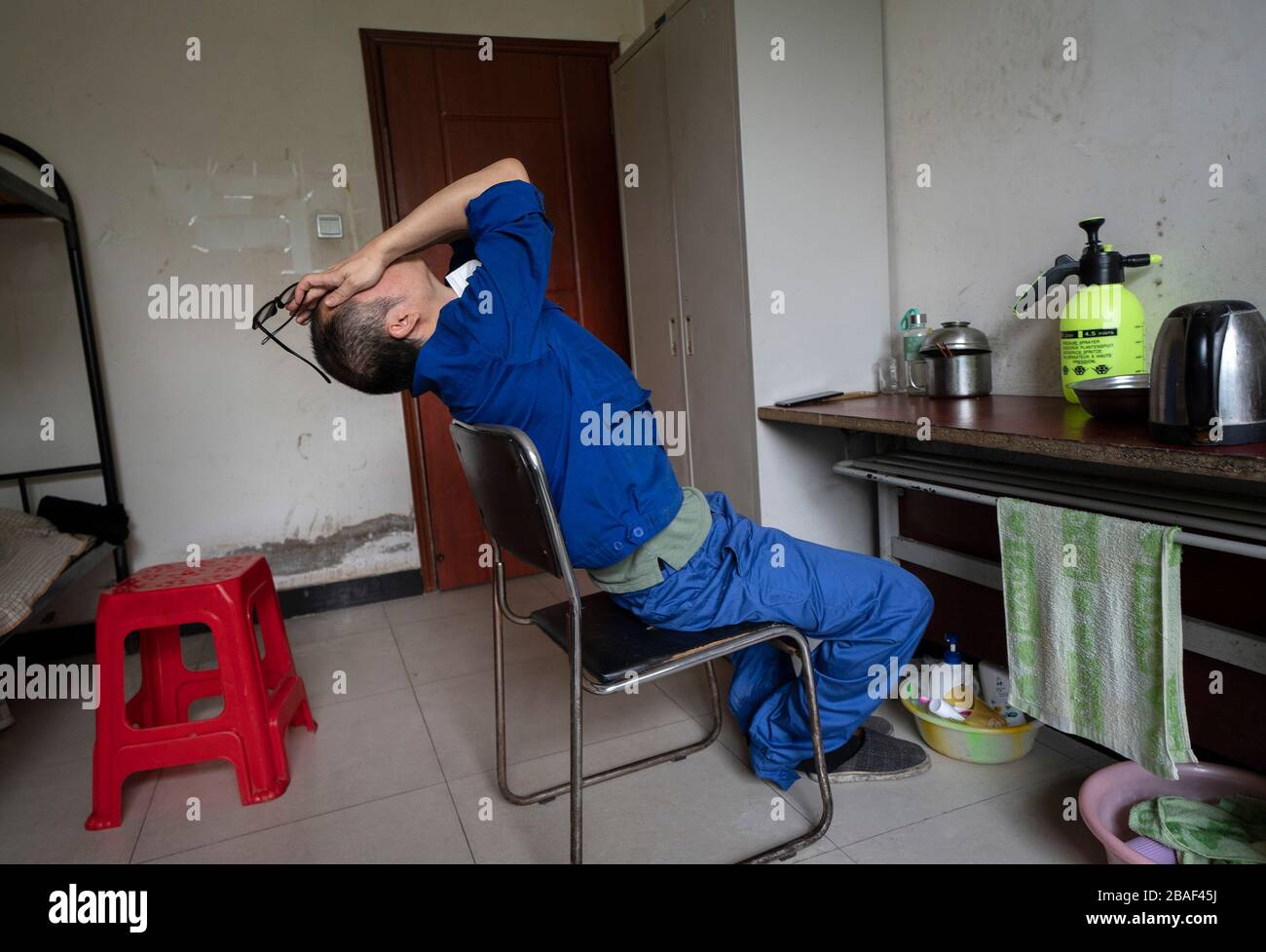 (200327) -- WUHAN, March 27, 2020 (Xinhua) -- Wang Peng stretches himself during lunch break in Wuhan, central China's Hubei Province, March 26, 2020. Wang Peng, 35, has been working for the Wuhan Hanshi Environmental Engineering Company for 9 years, where he is responsible for the disposal and incineration of medical waste.Protection against infection is a major challenge that Wang and his coworkers face, as they work 12-hour shifts to cope with the surging workload during the COVID-19 outbreak. 'I like what I'm doing,' Wang said, 'I'm not only making money for my family, but also making a co Stock Photo