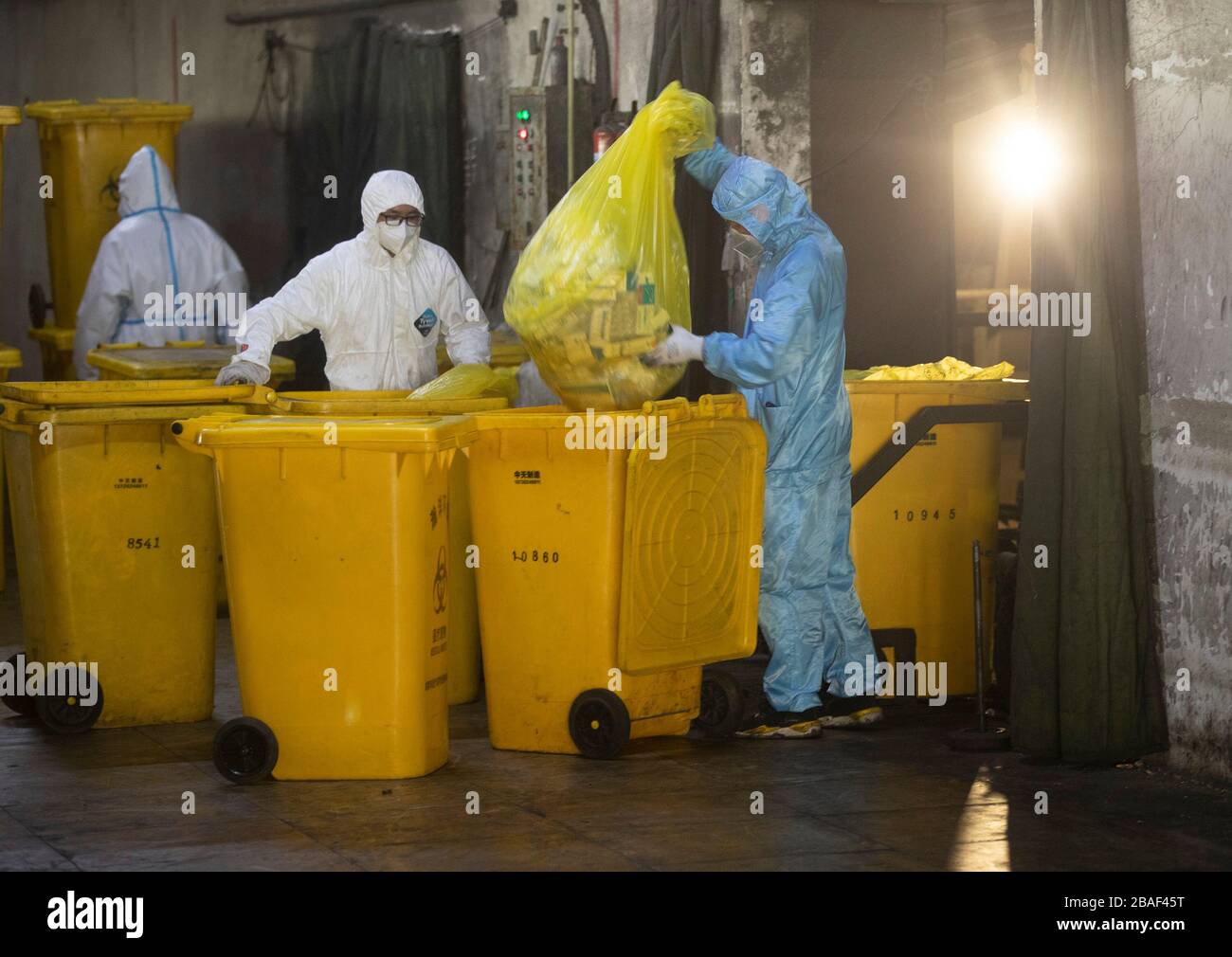 (200327) -- WUHAN, March 27, 2020 (Xinhua) -- Xia Shaohua (R), Wang Peng's colleague, takes out a bag of medical waste in Wuhan, central China's Hubei Province, March 26, 2020. Wang Peng, 35, has been working for the Wuhan Hanshi Environmental Engineering Company for 9 years, where he is responsible for the disposal and incineration of medical waste.Protection against infection is a major challenge that Wang and his coworkers face, as they work 12-hour shifts to cope with the surging workload during the COVID-19 outbreak. 'I like what I'm doing,' Wang said, 'I'm not only making money for my fa Stock Photo