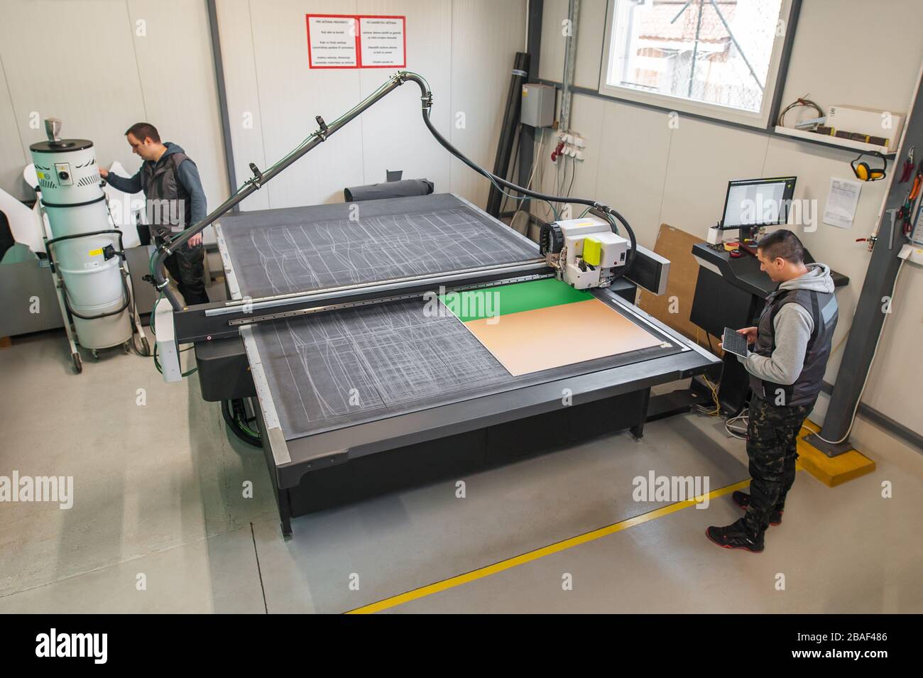 Two printshop worker technicians works on large CNC computer numerical control printing and cutting machine Stock Photo