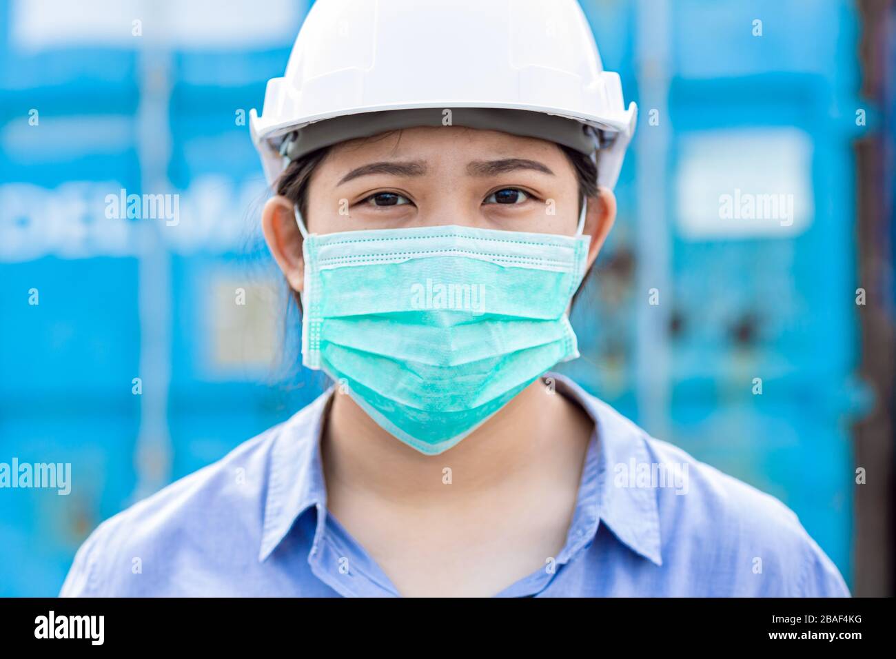 Asian worker wearing disposal face mask for protect dust smoke and corona virus while working in workplace. Stock Photo