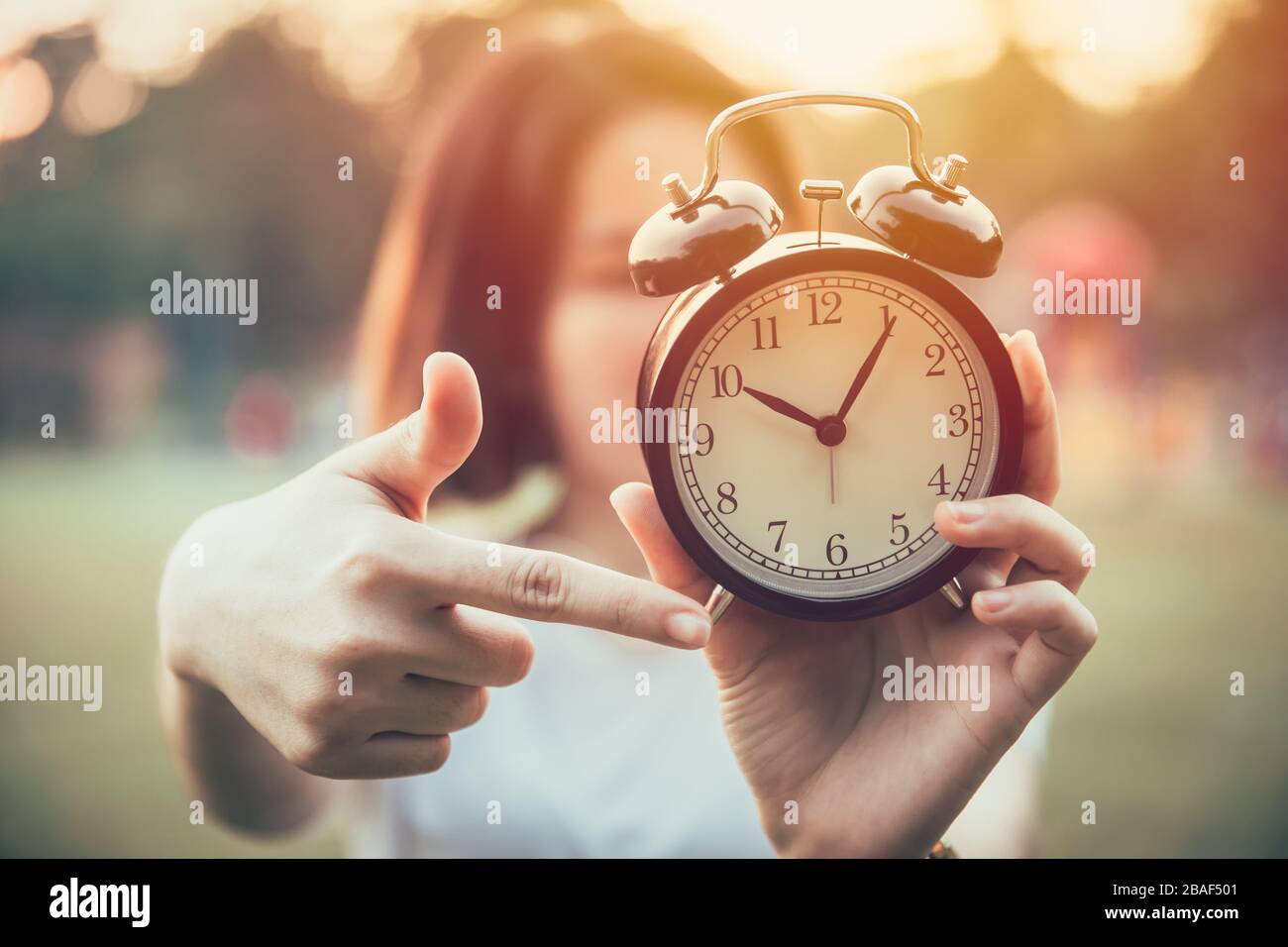 closeup hand pointing at clock times for It's time to do urgent or notice concept. Stock Photo