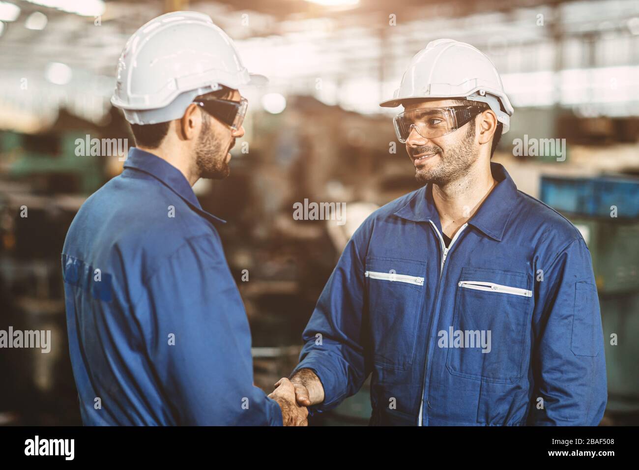 Worker engineer team smiling handshake for finish working dealing job done in factory industry background. Stock Photo