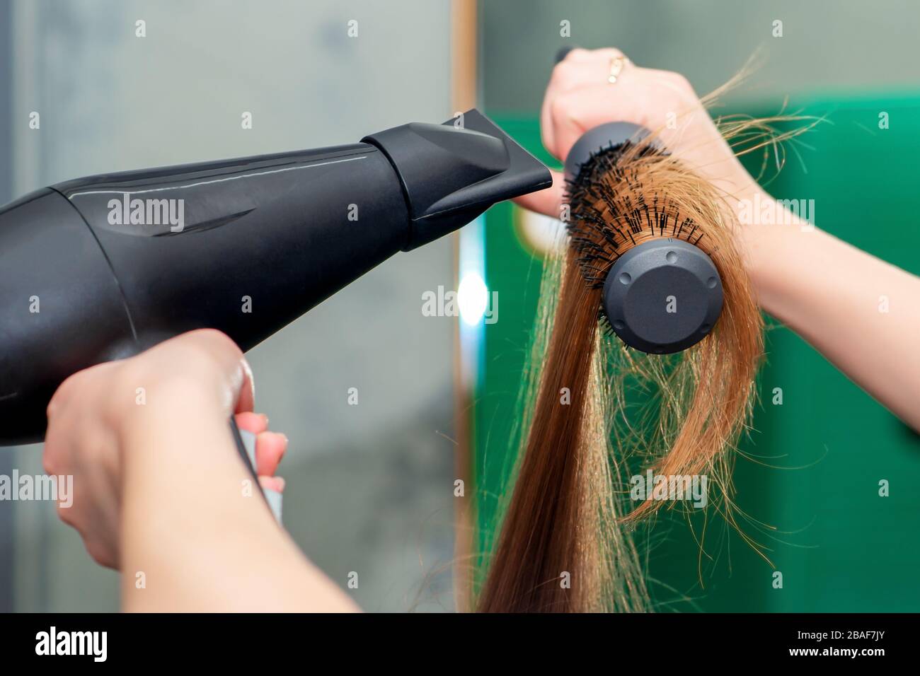 Hands of hairdresser dries long brown hair with hair dryer and round brush  close up Stock Photo - Alamy