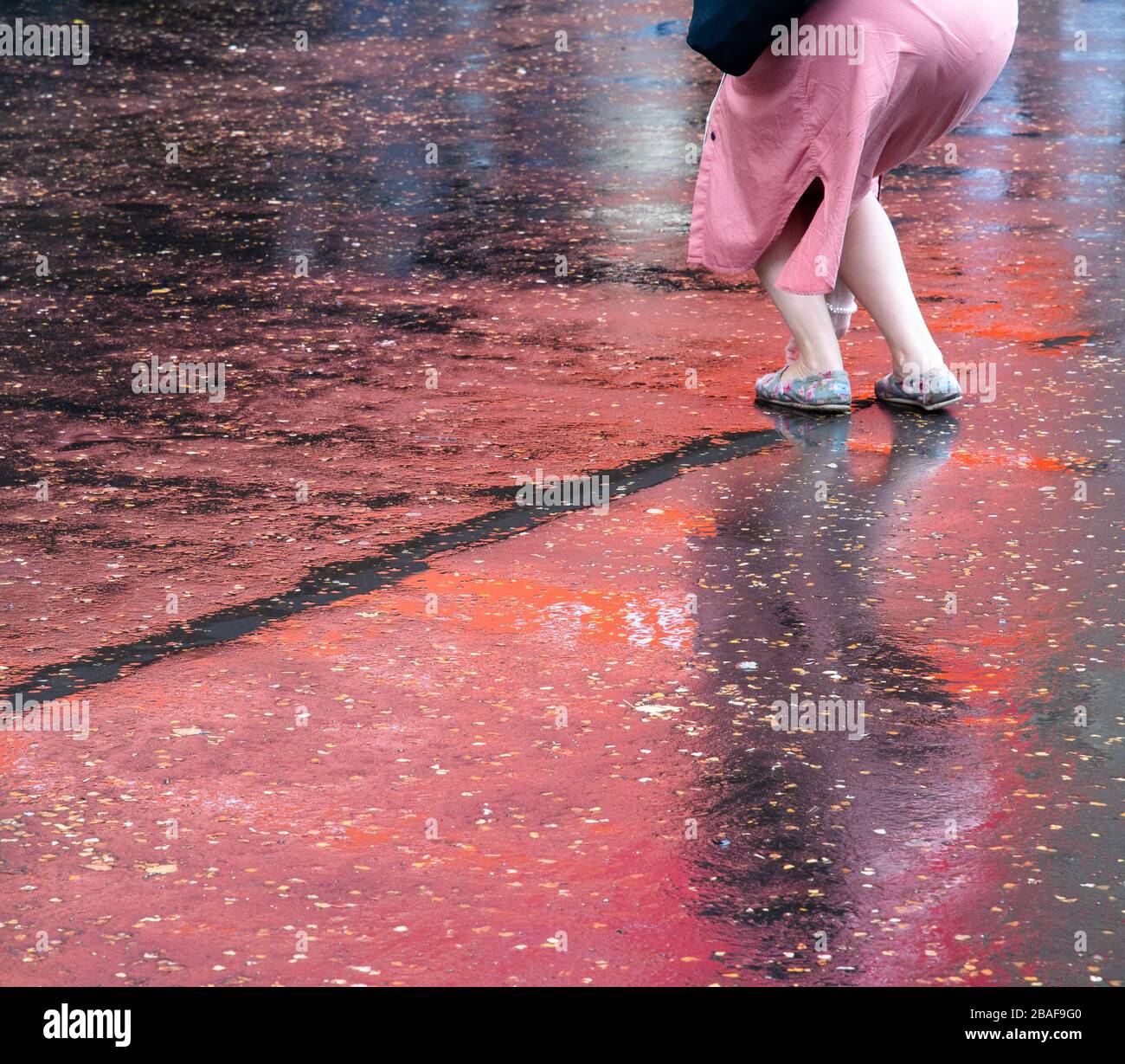 Reflection of woman in wet pavement Stock Photo