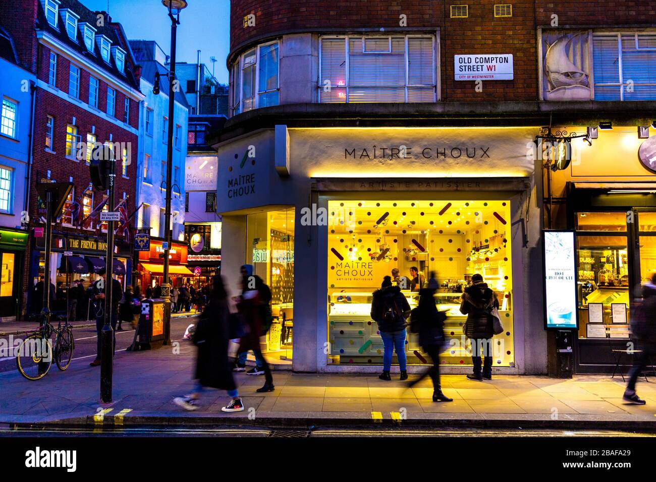 Busy Soho street in the evening and front of Maitre Choux patisserie eclair shop, London, UK Stock Photo