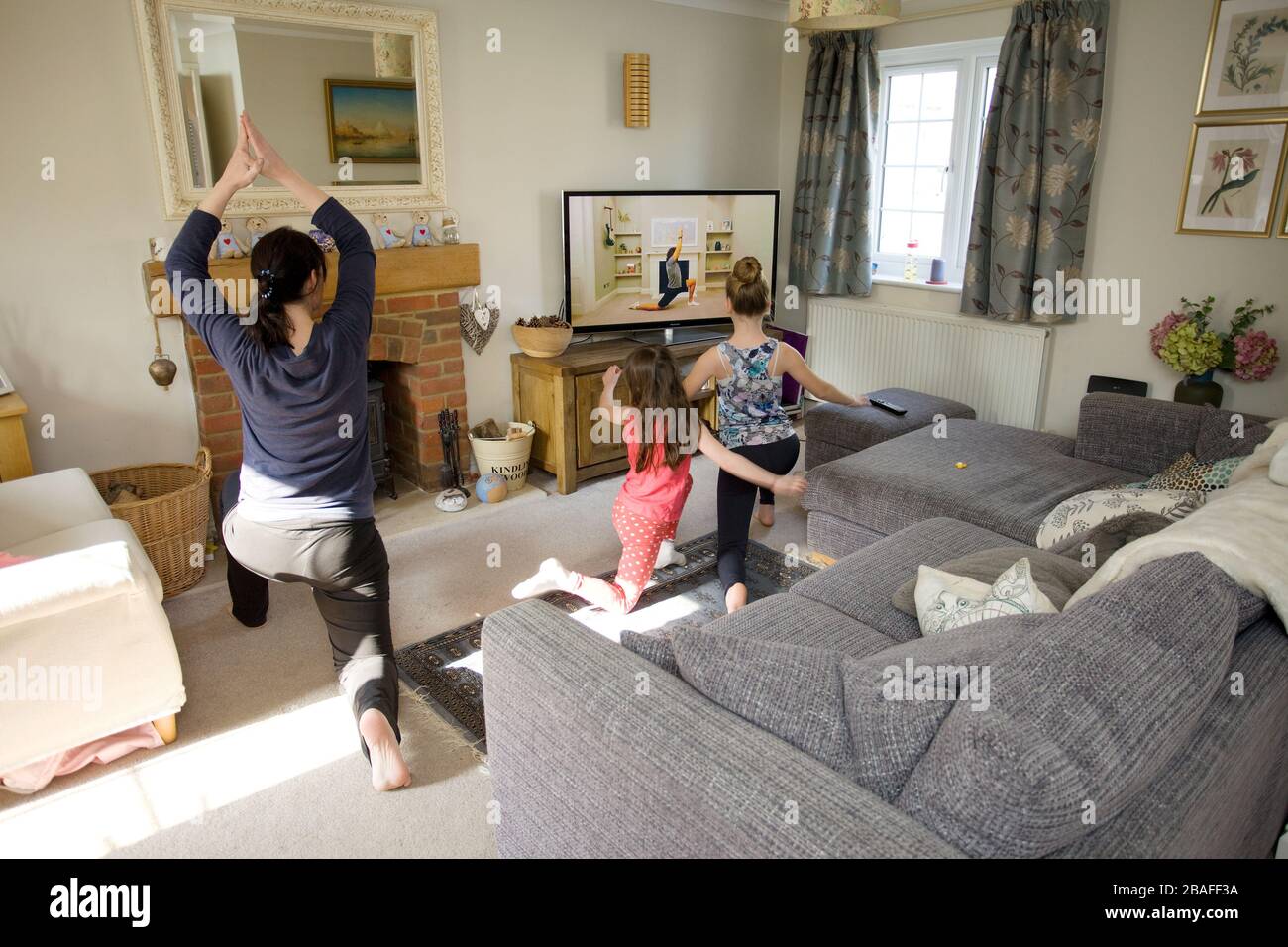 Young family exercising with live  Joe Wicks workout on the television in the  living room during coronavirus pandemic Stock Photo