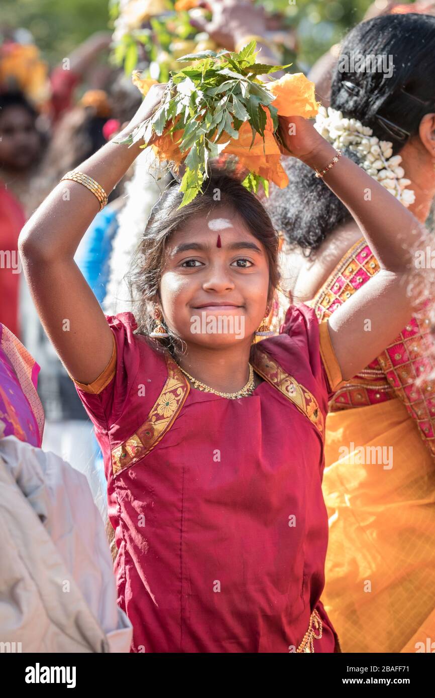 Young Hindu girl in sari participates in a colourful Chariot Festival procession carries offering on her head Stock Photo