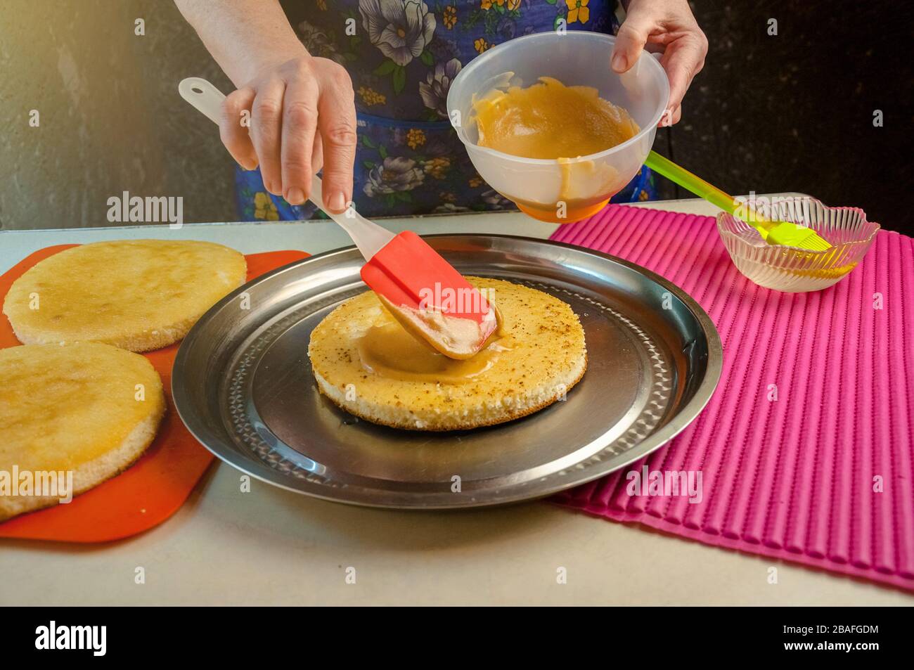 Baking Ingredients and Utensils for Cooking Sponge Cake. Process Cooking Sponge Cake. Woman Puts the Cream on the Cakes. Stock Photo