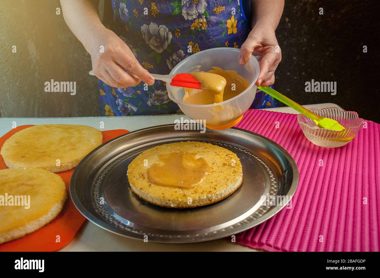 Baking Ingredients and Utensils for Cooking Sponge Cake. Process Cooking Sponge Cake. Woman Puts the Cream on the Cakes. Stock Photo