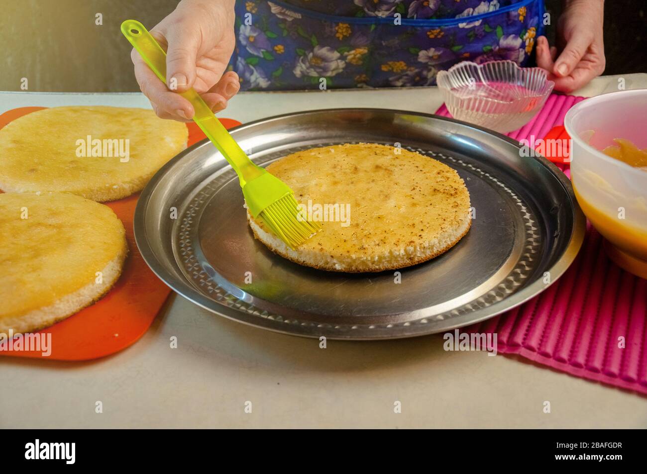 Baking Ingredients and Utensils for Cooking Sponge Cake. Process Cooking Sponge Cake. Woman Impregnates Syrup Cakes. Stock Photo