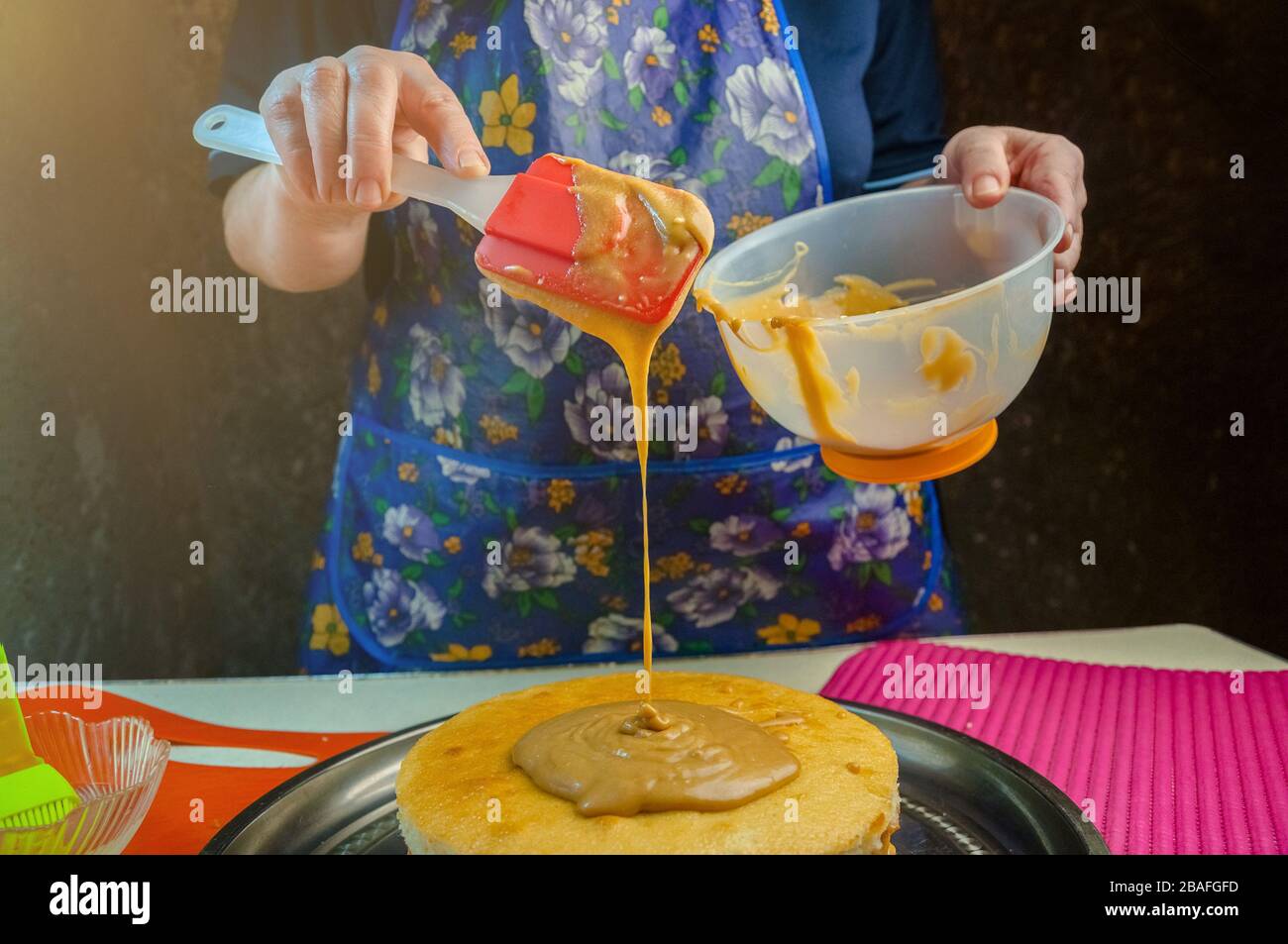 Baking Ingredients and Utensils for Cooking Sponge Cake. Process Cooking Sponge Cake. Woman Puts the Cream on the Cakes. Stock Photo