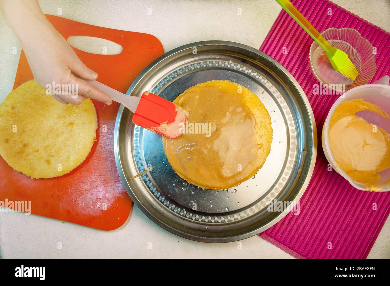 Baking Ingredients and Utensils for Cooking Sponge Cake. Process Cooking Sponge Cake. Woman Puts the Cream on the Cakes. Flat Lay Top View. Stock Photo