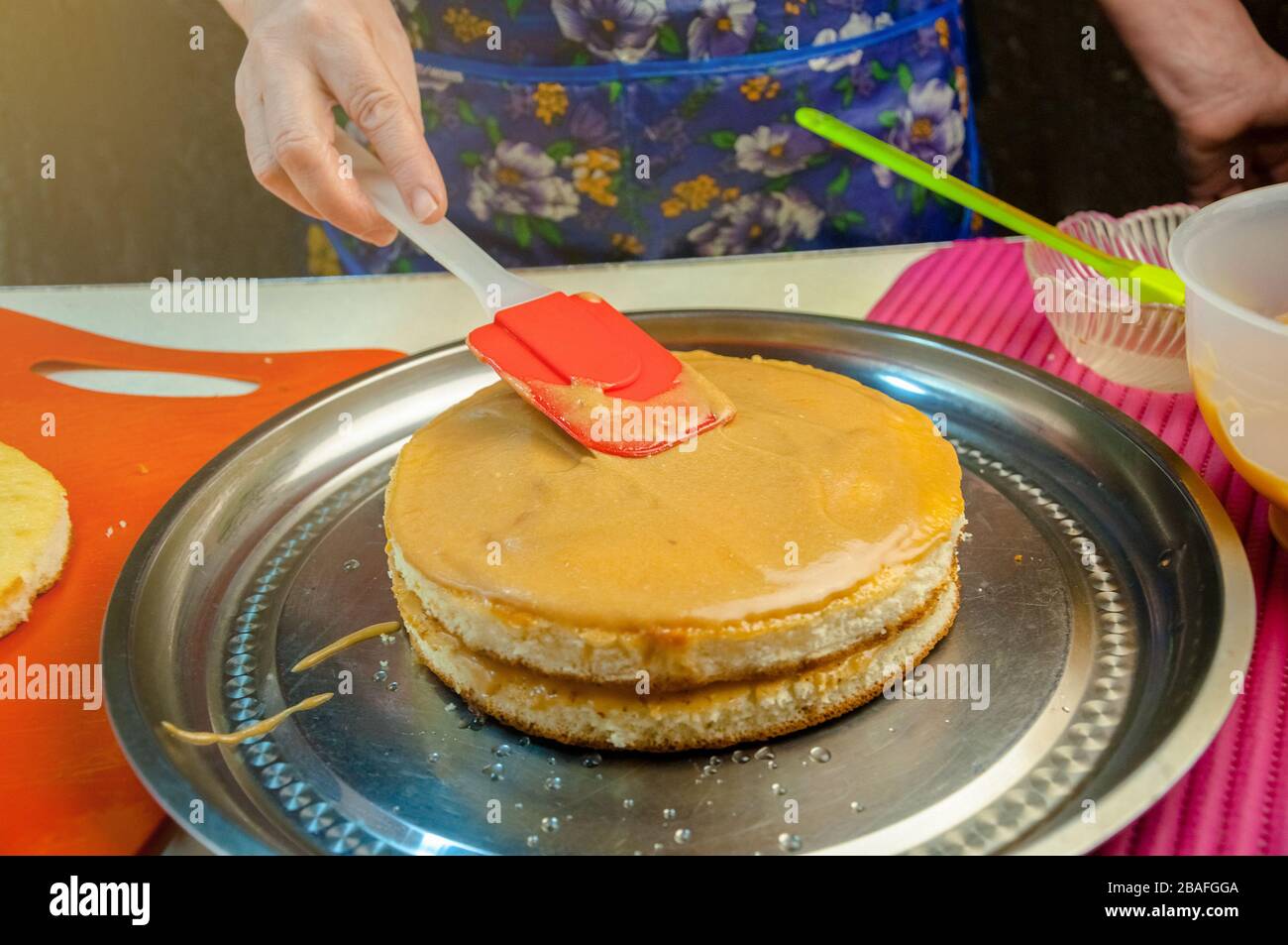 Baking Ingredients and Utensils for Cooking Sponge Cake. Process Cooking Sponge Cake. Woman Puts the Cream on the Cakes. Stock Photo