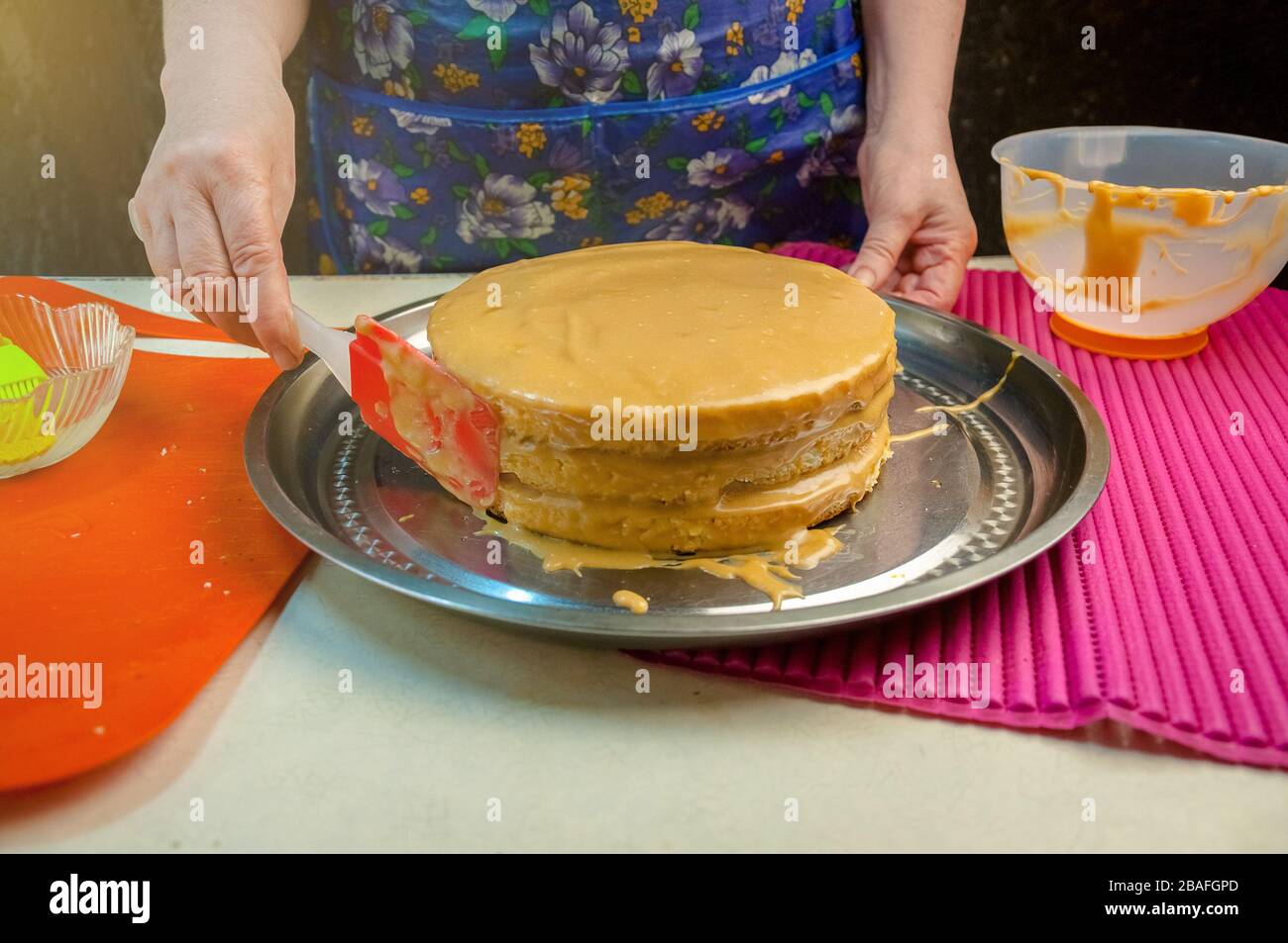 Baking Ingredients and Utensils for Cooking Sponge Cake. Process Cooking Sponge Cake. Woman Puts the Cream on the Cakes. Stock Photo