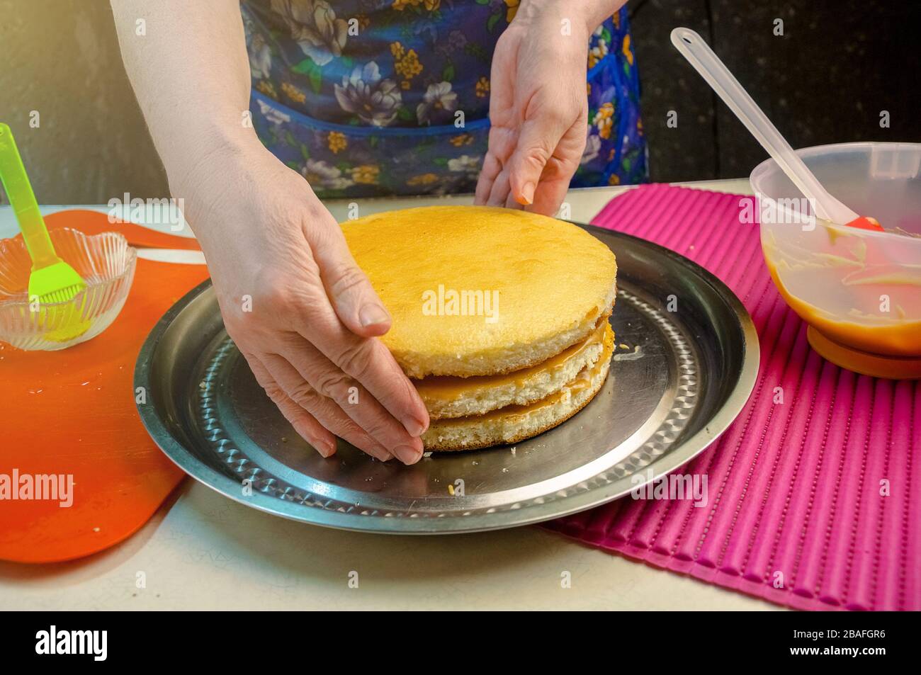 Baking Ingredients and Utensils for Cooking Sponge Cake. Process Cooking Sponge Cake. Woman Forms a Cake. Stock Photo