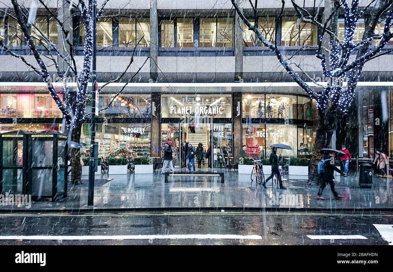 Planet Organic. A busy London street scene with Christmas shoppers on Tottenham Court Road on a cold and snowing winters day. Stock Photo